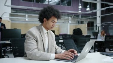 Afrikalı Amerikalı adam modern ofis alanında yıllık mali rapor hazırlıyor. Bilgisayarda yazı yazan ciddi bir girişimcinin yakın plan görüntüsü. Yüksek kalite 4k görüntü