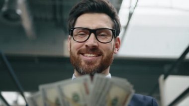 Resmi takım elbiseli, gülümseyen, mutlu bir iş adamının yakından görüntüsü. Beyaz adamın portresi. Finansal başarısının keyfini çıkarıyor ve içeride para sayıyor. Yüksek kalite 4k görüntü