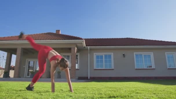 运动员进行体操运动 使她的身体向地面倾斜 女人在做沙拉 在室外旋转身体 高质量的4K镜头 — 图库视频影像