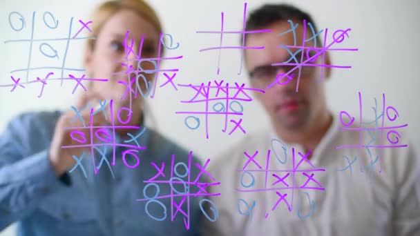 男人和女人在一个有彩色记号的玻璃板上玩游戏 两名玩家轮流将O或X放置在九个正方形的模式中 高质量的4K镜头 — 图库视频影像