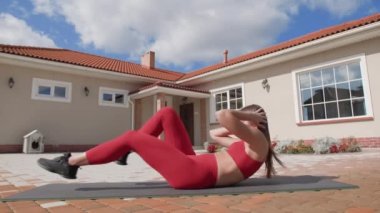 Kız kollarını kafasının arkasında çapraz yapıp karın kaslarını kullanarak gövdesini kaldırıyor. Bisiklet mekiği çeken bir bayan sporcu. Yüksek kalite 4k görüntü