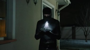 Bir hırsızın tutuklamak için ellerini kaldırdığını yakın plan görüntüsü. Dışarıda kar maskeli tanınmayan bir adam çalıntı paraları sayıyor. Yüksek kalite 4k görüntü