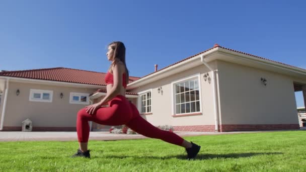 女性は屋外の自宅のジムで肺をしています 若い女性選手は低い体を強化するために抵抗運動を行う 高品質4K映像 — ストック動画