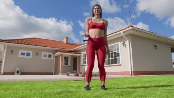 彼女の家の庭で屋外で上体運動をしている女性 バックグラウンドで美しい建物で彼女の腕を訓練女性選手 高品質4K映像 — ストック動画