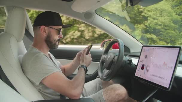 ウクライナのキエフ 2021年8月 男性ドライバーはスマートフォンを使い テスラ オートパイロットは車を運転する レーダーを使用して無人運転車技術は 周囲を分析します 高品質4K映像 — ストック動画
