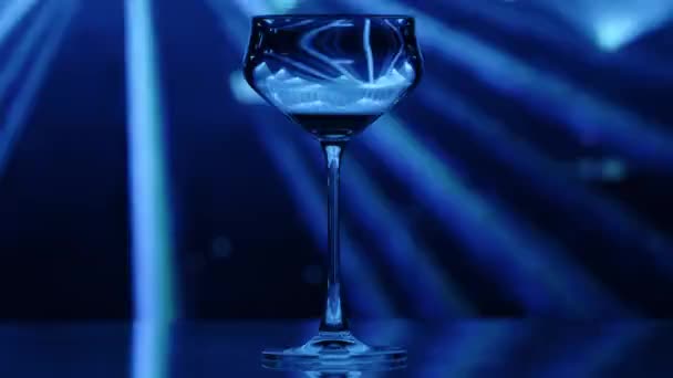 Klares Weinglas Steht Vor Einer Schwärmerischen Blau Gefärbten Lichtshow Die — Stockvideo