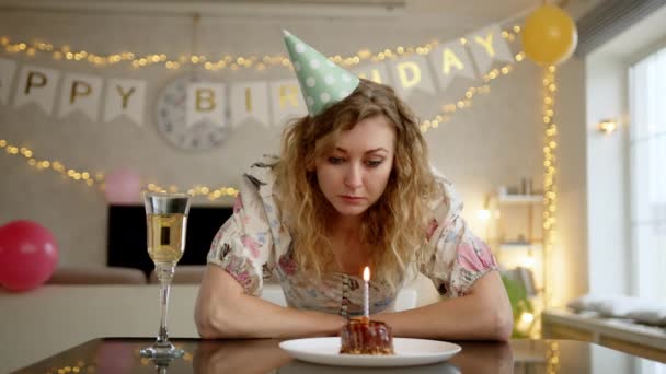 素敵なドレスと誕生日ケーキを見て誕生日キャップの悲しい女性 彼女は部屋に一人でいて何かに動揺しているようです 高品質4K映像 — ストック動画