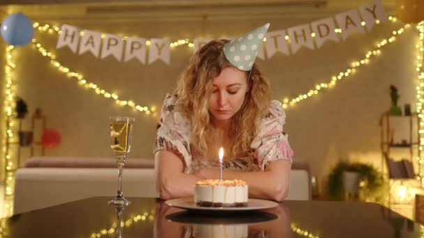 Een Trieste Vrouw Een Mooie Jurk Een Verjaardagsmuts Zit Met — Stockvideo
