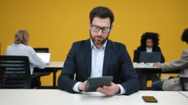 Hesap makinesi kullanan, 40 'lı yaşlarda, ciddi bir beyaz adamın yakın çekim görüntüsü. Gözlüklü sakallı bir adamın portresi modern ofis alanındaki kârını analiz ediyor. Yüksek kalite 4k görüntü