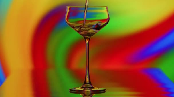 Das Klare Glas Wird Vor Einem Bunten Kurvigen Regenbogenhintergrund Gefüllt — Stockvideo