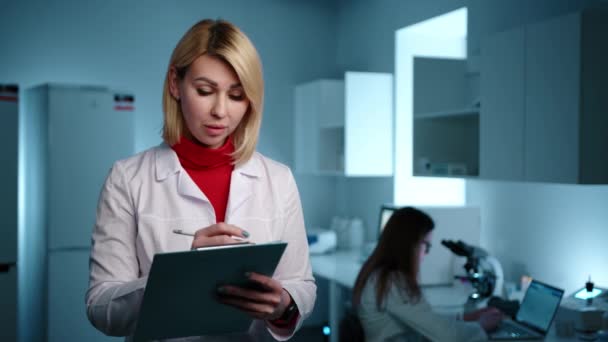 Blonde Veterinarian Laboratory Writing Something Tablet Another Doctor Working Microscope — Stock Video