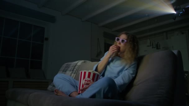 年轻的高加索女人在家里看3D电影 戴眼镜的女人坐在沙发上吃爆米花 高质量的4K镜头 — 图库视频影像