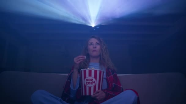 头发卷曲的女人在放映机上看音乐会 吃爆米花 在家里的沙发上跳舞 高质量的4K镜头 — 图库视频影像