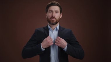 Takım elbiseli bir adam yüzünde bir gülümsemeyle ceketini düzeltiyor. Güzel giyinmiş ve çok mutlu görünüyor. O, kahverengi bir arka plandadır. Yüksek kalite 4k görüntü