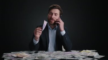 Takım elbiseli bir adam telefonda konuşurken bir dolar banknotundan kağıt bir uçağı fırlatıyor. Mutlu görünüyor. Adam siyah odada yatıyor. M, oney büyük bir yığın içinde. Yüksek kalite 4k görüntü 