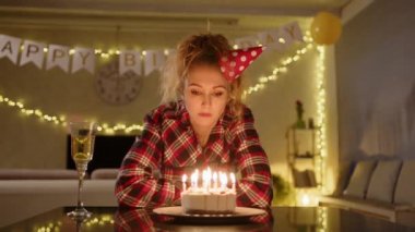Doğum günü pastasına bakıp üzerine mum üfleyen üzgün bir kadın muhtemelen yaşlanmasına ya da yanında kimsenin olmamasına üzülüyordur. yüksek kalite 4k görüntü