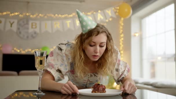 誕生日のケーキの上に狩りをし 一口を取る前にそれにろうそくを吹いて女性 彼女は視覚的に何かを悲しんでいる 高品質の4K映像 — ストック動画