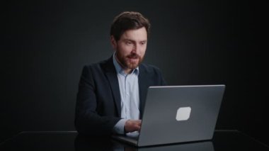 Siyah takım elbiseli bir adam hücreden para düşerken laptopun önünde tezahürat yapıyor. Çok mutlu görünüyor. O, siyah bir odada. Yüksek kalite 4k görüntü