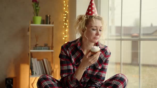 Parti Şapkası Takmış Bir Kadın Pencerenin Yanında Oturup Çöreğe Bakar — Stok video