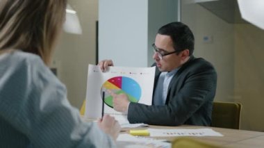 Erkek CEO 'nun bayan asistanına yeni veriler gösterdiği yakın çekim görüntüsü. Meslektaşıyla işbirliği yapan başarılı iş adamının portresi. Yüksek kalite 4k görüntü