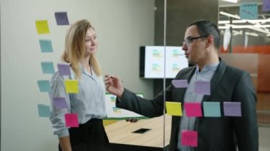 İş ortaklarının çıkartmalar hakkında yeni fikirler yazdıkları yakın plan çekimler. Kafkas erkek ve kadın portresi modern ofis alanında beyin fırtınası yapıyor. Yüksek kalite 4k görüntü