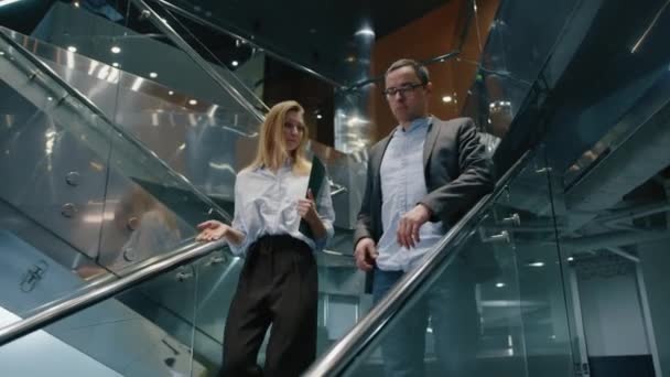 現代的なビジネスセンターの階段を歩いている男性と女性の近くのビュー 会議に向かっている間 同僚がチャット 高品質4K映像 — ストック動画