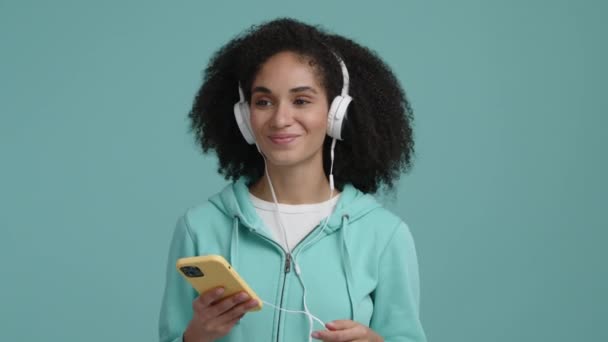 快乐的女孩 卷曲的 民族的头发听音乐 一个戴着白色耳机拿着电话的快乐女人的近照 高质量的4K镜头 — 图库视频影像