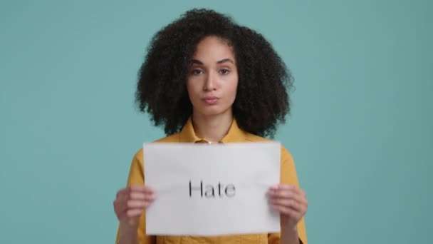 一个年轻的黑发女士拿着一张带有攻击性面部表情的白卡的特写镜头 心烦意乱而忧郁的女孩感到憎恨 高质量的4K镜头 — 图库视频影像