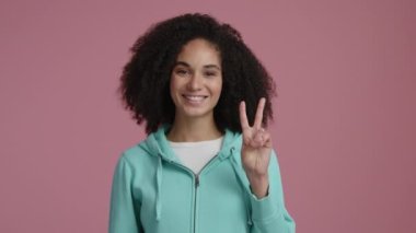 Kapalı mekanda karşılama jesti yapan mutlu kadının portresi. 30 'lu yaşlarındaki güzel, gülümseyen bir kadın günlük kıyafetler giyiyor ve gülüyor. Yüksek kalite 4k görüntü