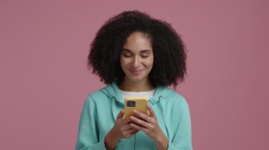 İyi haberler alan ve mutlu görünen genç bir kadının portresi. Kıvırcık saçlı neşeli kız mesaj yazıyor. Yüksek kalite 4k görüntü