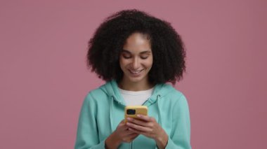 Aptal ve neşeli görünen genç bir yetişkinin portresi. Akıllı telefonunu tutarak iletişim kuran bir kadın. Yüksek kalite 4k görüntü