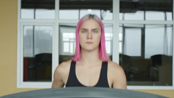 集中的なワークアウト中に女性アスリートジョギングに焦点を当てた ピンクの髪の美しい若い女性は 減量のためにトレッドミル上で実行しています 高品質4K映像 — ストック動画