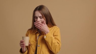 Kafkasyalı bir kadının gündelik kıyafetlerle yakın çekimi. Kadın öksürmemek için kağıt bardaktan su içiyor. Yüksek kalite 4k görüntü