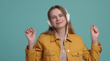 Gülümseyen ve gülen 30 'lu yaşlarındaki beyaz kız, müzik listesinin tadını çıkarıyor. Kulaklıkla müzik eşliğinde dans eden bir kadının yakın plan görüntüsü. Yüksek kalite 4k görüntü