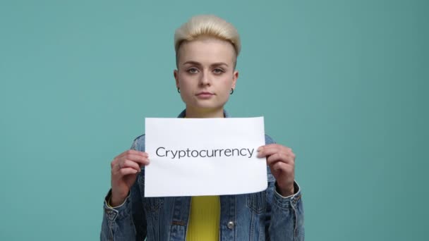 カジュアル服の白人女性は暗号通貨の言葉で白い紙を持っています 暗号投資を宣伝する少女の肖像画 高品質4K映像 — ストック動画