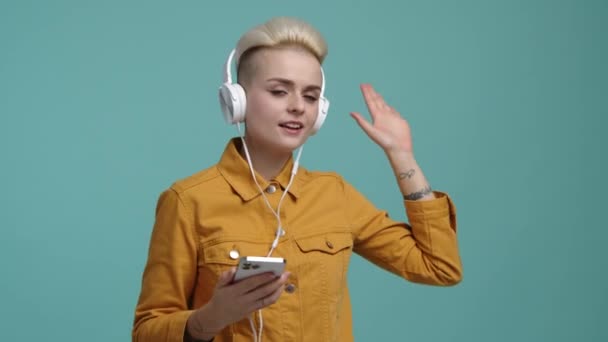 一个女人在房间里跳舞唱歌的画像 一个30多岁的白种人 金发女孩 一边拿着电话一边在网上播放音乐 高质量的4K镜头 — 图库视频影像