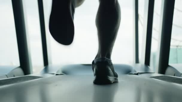 男足适合肌肉 从膝盖到脚趾都穿着黑色运动鞋在健身房的跑步机上奔跑 慢动作小牛犊运动 背景是白昼 高质量的4K镜头 — 图库视频影像