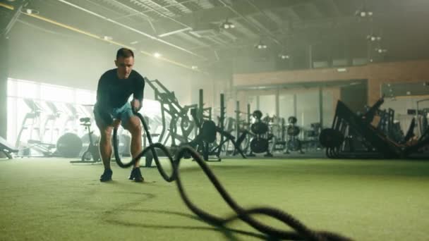 ジムで運動選手によって行われた戦闘ロープ上のスラムとの組み合わせで上のカット 背景にはエアバイク トレッドミル ローイングマシン バーベル 高品質4K映像 — ストック動画