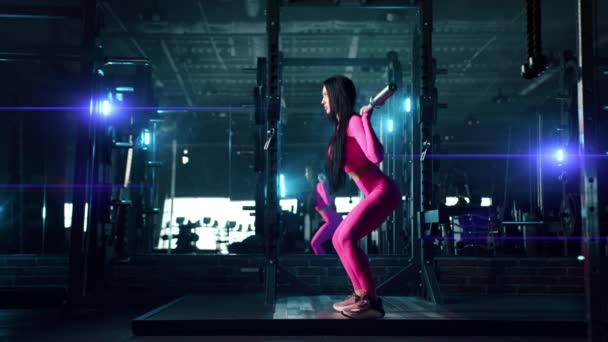 ダークライトアップされたジムでバックスクワットバーベルを行う運動女の側面図 背景に大きな鏡 ピンクのスポーツウェアはフィット感を強調 高品質4K映像 — ストック動画