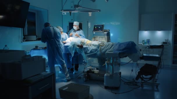 长时间的整形手术 病人躺在手术台上麻醉 医护人员在灯光昏暗的手术室工作 高质量的4K镜头 — 图库视频影像