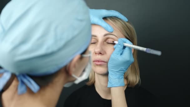 女性患者和女医生在进行面部手术标记的过程中肩部被射中 医生在上眼睑上画了线 眼睛闭上了 高质量的4K镜头 — 图库视频影像