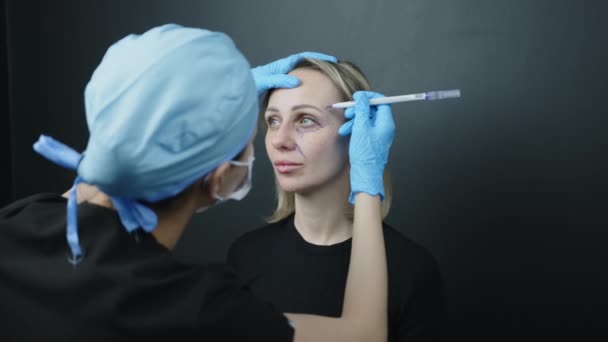 在面对外科标识的过程中 妇女和医生的肩部被射中 医生小心地在庙宇上做记号 眼底有记号鼻唇有褶皱高质量的4K镜头 — 图库视频影像