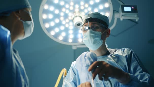 在整形手术过程中 医生和护士肩膀上的照片 外科医生仔细地看了看 领导操作剧场灯光在后台 高质量的4K镜头 — 图库视频影像