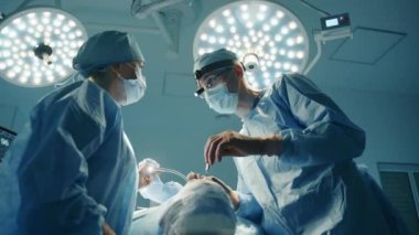 Genç erkek cerrah ve bayan hemşire estetik ameliyat sırasında dostça sohbet ediyorlar. Operasyon ışıkları olan ameliyathane. Yüksek kalite 4k görüntü