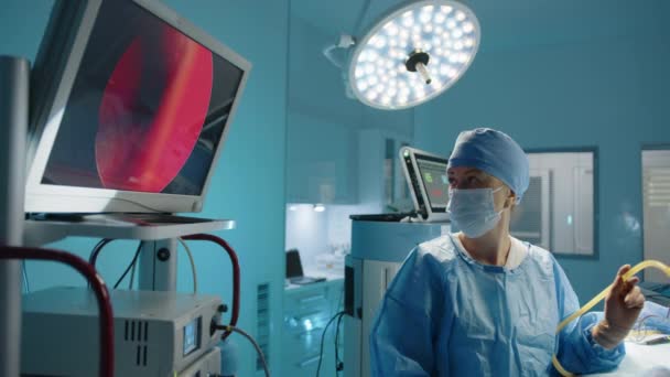 年轻的女护士在整形手术过程中看着监视器 手术室设备齐全 灯火通明 高质量的4K镜头 — 图库视频影像