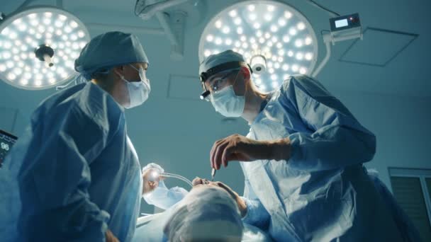年轻的男医生和女护士在整形手术过程中进行友好的交谈 手术室有领先的手术室灯光 高质量的4K镜头 — 图库视频影像