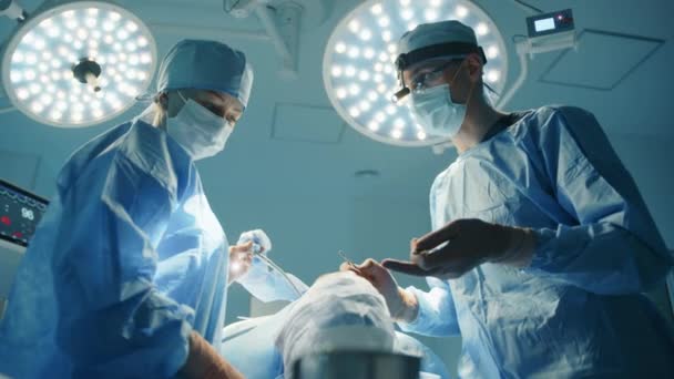 年轻的男性外科医生在整形手术期间给护士提供指导 病人正处于麻醉状态 领导行动剧院灯光聚焦 高质量的4K镜头 — 图库视频影像