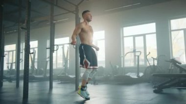 Spor salonunda çıplak bedeniyle halata atlayıp boks maçına hazırlanan atletik bir genç. Sporcu, tam teçhizatlı spor salonunda tek başına çalışır. Yüksek kalite 4k görüntü
