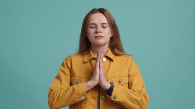 Genç bayan dua ederken odaklanmış görünüyor. Günlük kıyafetlerle meditasyon yapan beyaz bir kadını yakından çek. Yüksek kalite 4k görüntü