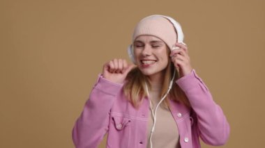 Şapka takıp müzik dinleyen neşeli bir kadının portresi. Beyaz kadın şarkı söyleyip dans ediyor. Yüksek kalite 4k görüntü